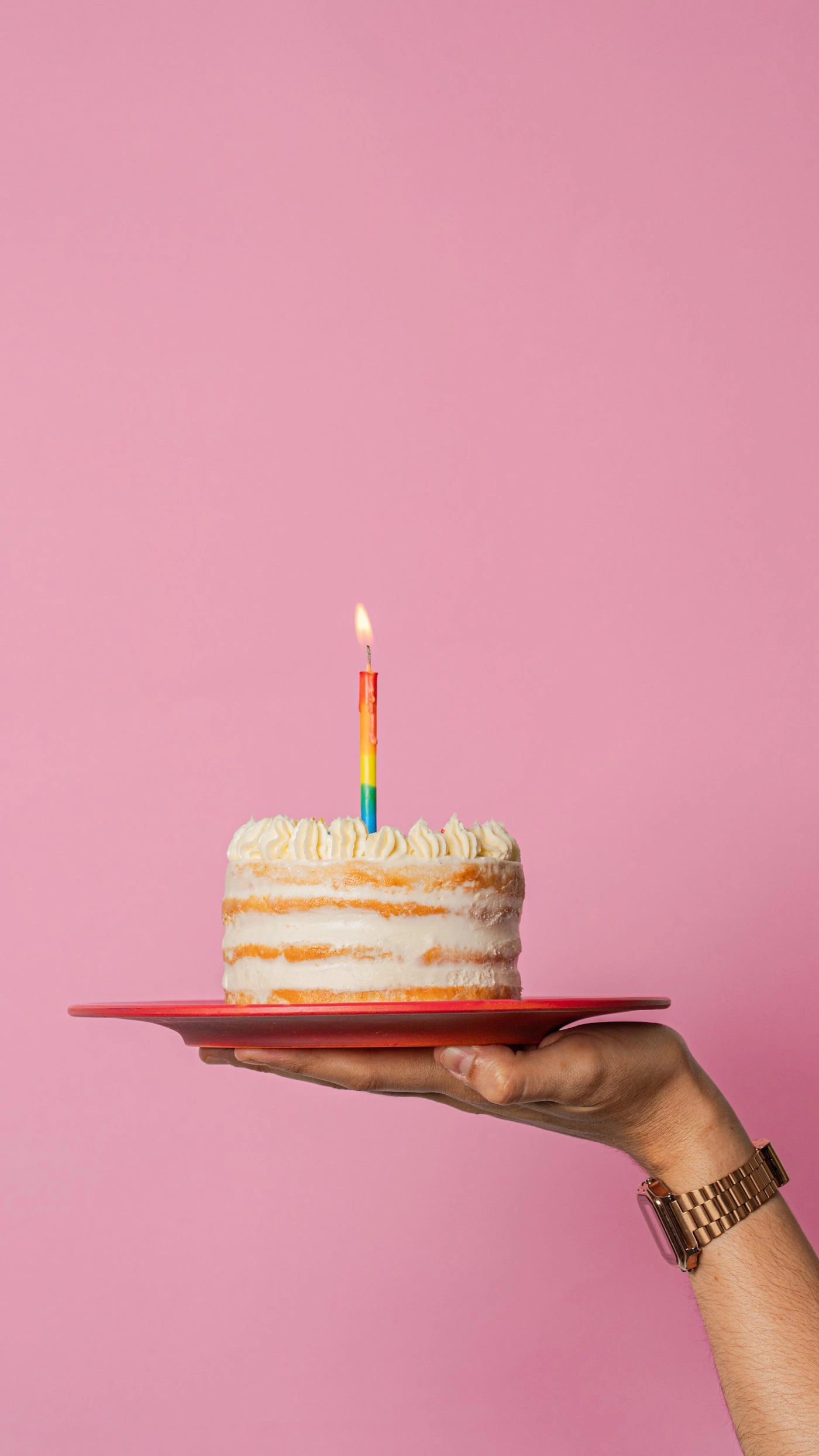 Pastel de cumpleaños con vela sobre fondo rosado