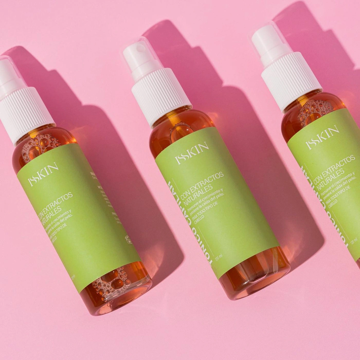 Tres sprays de Isskin sobre fondo rosa con sombras marcadas