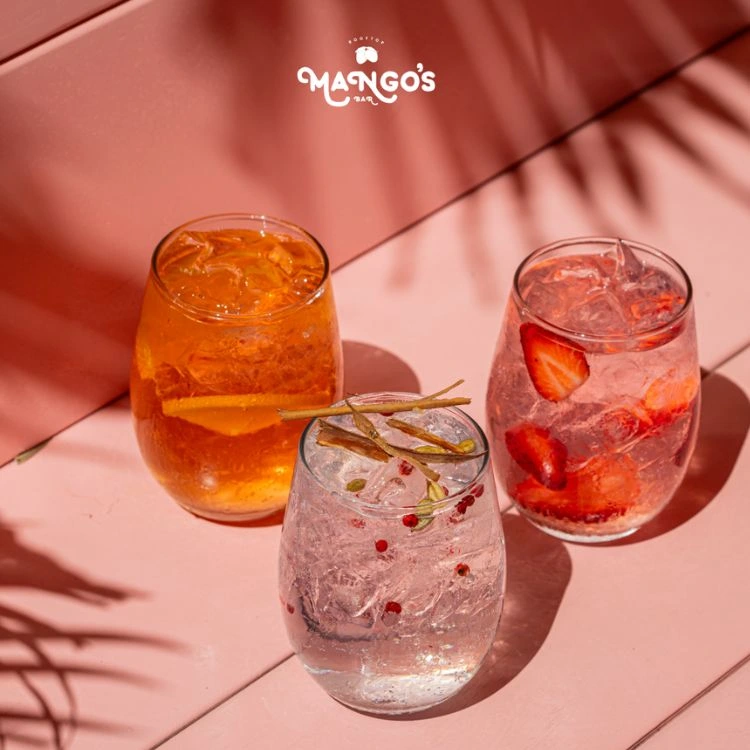 Tres bebidas frutales de Mango’s sobre una mesa rosada