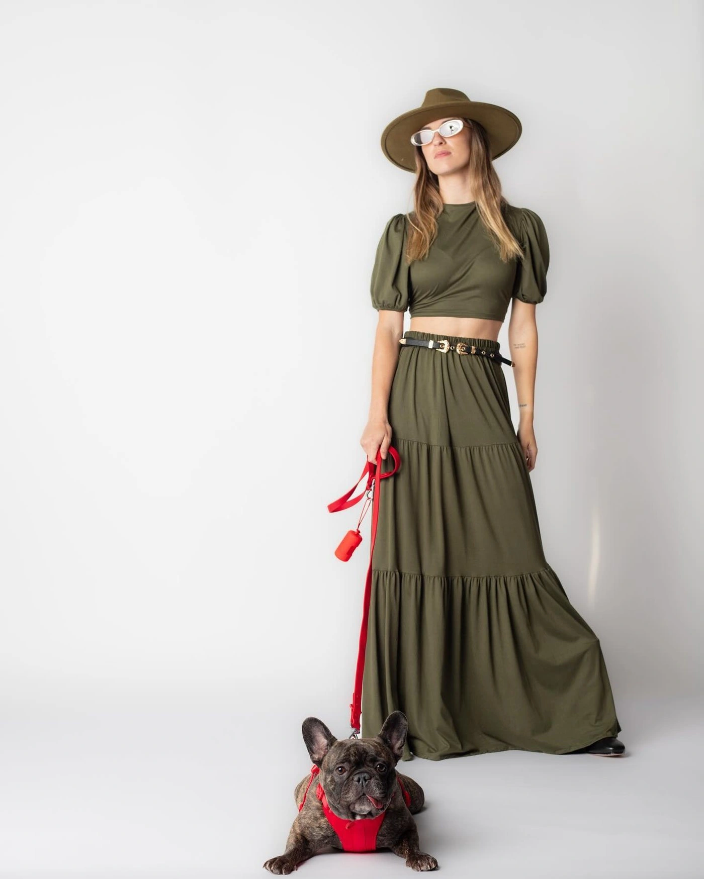 Modelo con sombrero y vestido verde junto a un bulldog